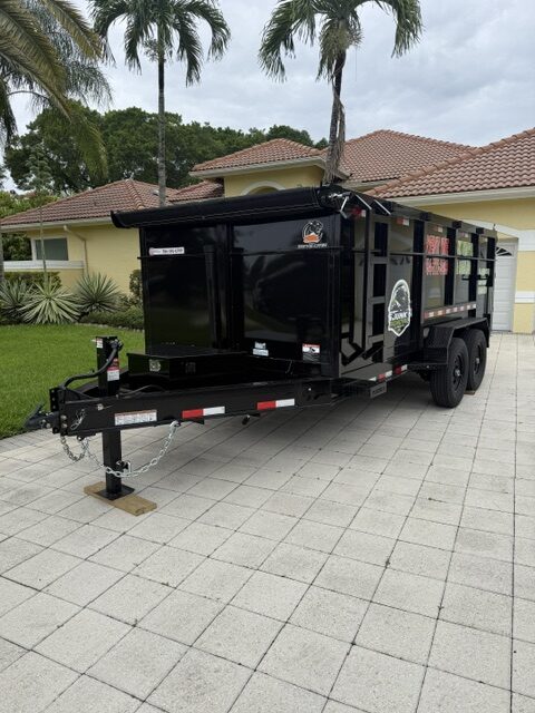 Black dump trailer rental parked in a Hollywood FL residential driveway